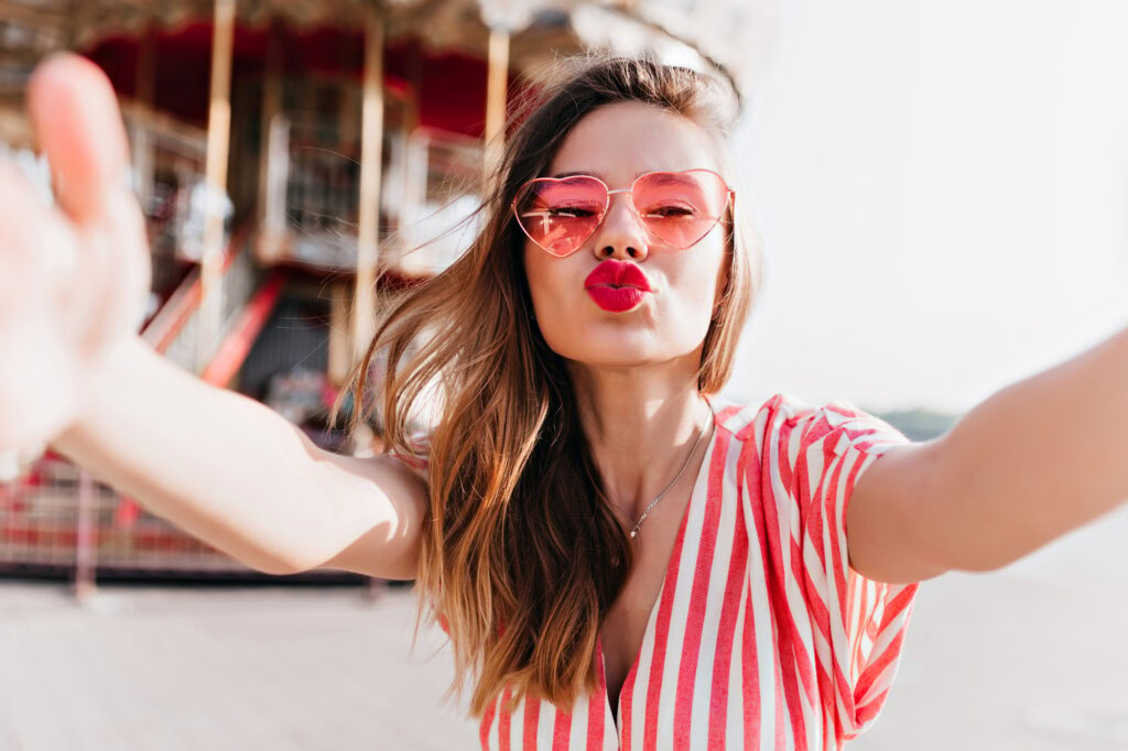 Gorgeous white girl posing in amusement park with kissing face expression | SUPERPOBYT Travel