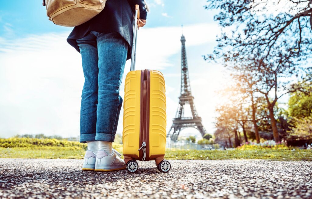 Happy tourist with luggage visiting Eiffel Tower in Paris, FranceAt the Eiffel tower in Paris, France Gorgeous white girl posing in amusement park with kissing face expression | SUPERPOBYT Travel