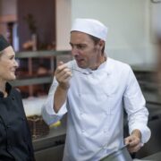 Chefs chatting and tasting food in kitchen