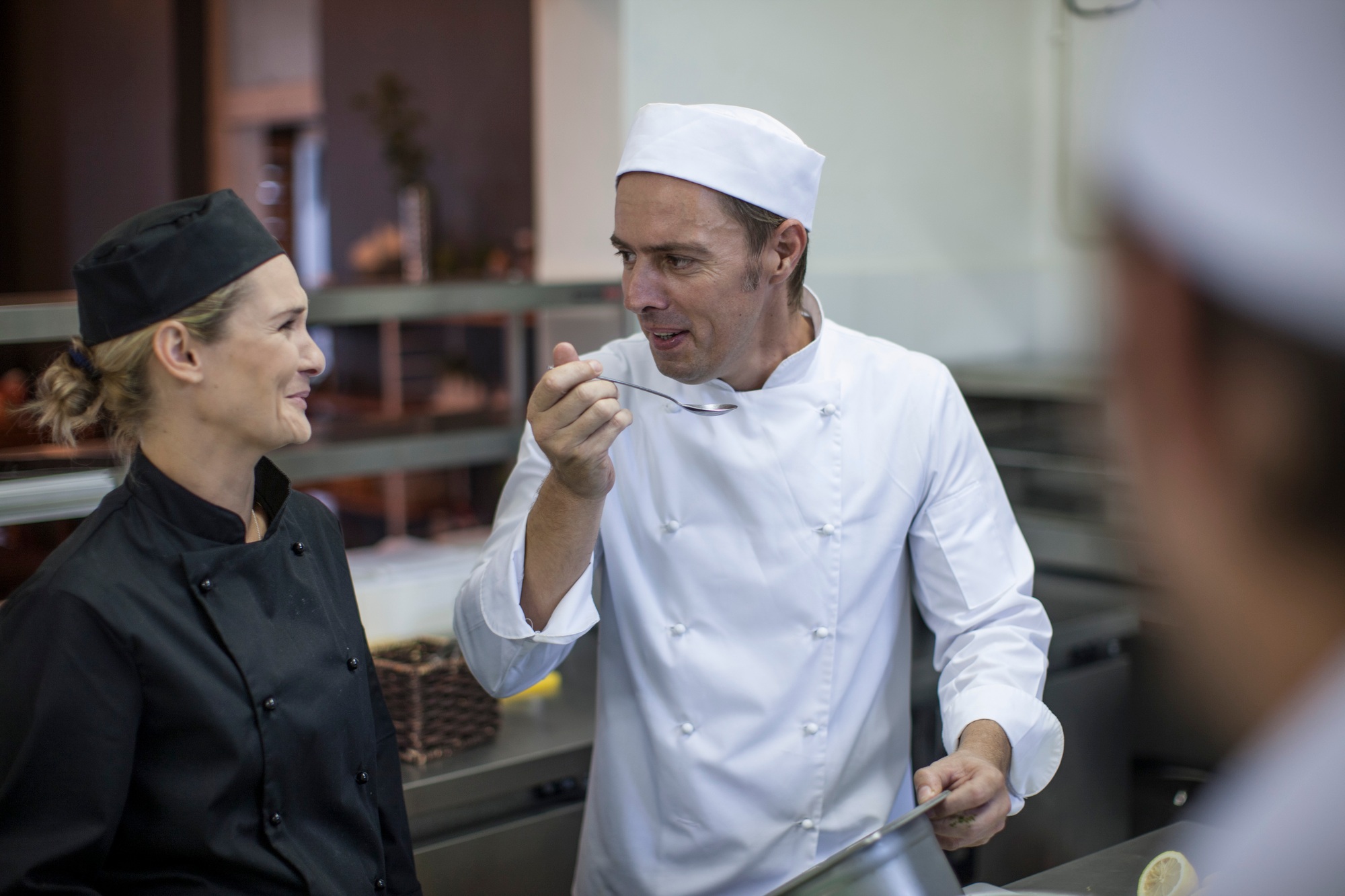 Chefs chatting and tasting food in kitchen