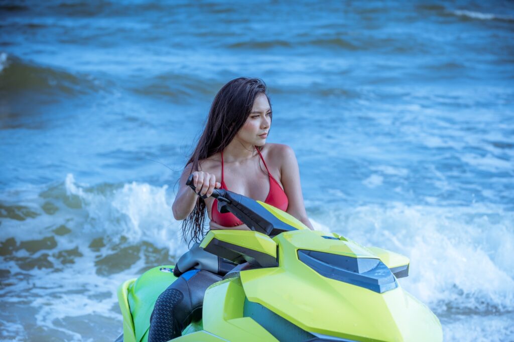 Portrait sexy model wearing bikini and drive jet ski is sport speed boat on sea.